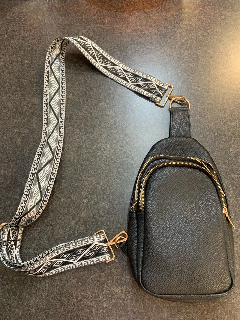 Black Crossbody Sling Bag with Patterned Strap and Gold Hardware Accents